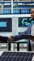 Vertical Solar panel factory manager shaking hands with investor interested in manufacturing process. Man greeting shareholder visiting photovoltaics plant to see production growth data, doing handshake, camera A video