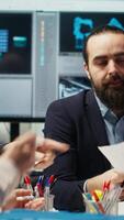 Vertical Business executives meet with investors to discuss the integration of automation technology in solar panel production processes, looking over paperwork and schematics, camera B video