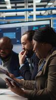 Vertical Factory manager works on integrating automation technology in industrial plant, looking at device. African american woman analyzing business model data on tablet, expanding production, camera A video