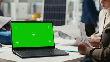 Businesspeople in office do financial investments, looking at chroma key notebook. Management executives look at production scaling automation strategies on isolated screen laptop, closeup video