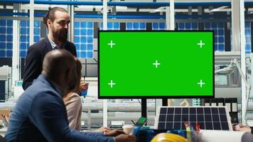 Photovoltaics plant researchers doing meeting, looking at green screen monitor, evaluating energy production. Experts optimize factory equipment energy output, looking at mockup display, camera B video