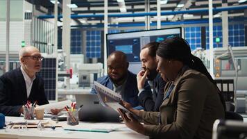 Factory manager works on integrating automation technology in industrial plant, looking at device. African american woman analyzing business model data on tablet, expanding production, camera A video