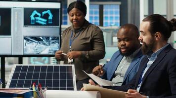 Shareholders discussing future investment opportunities in sustainable energy manufacturing. Management executives and investors in solar panels plant reviewing solar technology reports, camera B video