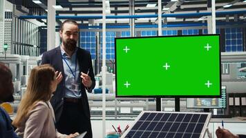 Photovoltaics plant researchers doing meeting, looking at green screen monitor, evaluating energy production. Experts optimize factory equipment energy output, looking at mockup display, camera A video