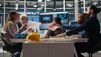 Industrial plant management looking over paperwork and schematics. Factory executives meet with investors to discuss integration of automation technology in production, camera A video