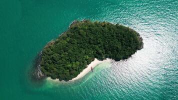 Aerial view of a sailboat floating around an exotic heart shaped small island, amazing shape with palm trees and a sandy beach around the turquoise waters. Tropical landscape. video