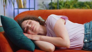Tired young woman girl lying down in bed taking a rest at home, napping, falling asleep on couch video