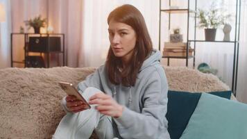 Upset woman showing dislike gesture while using smartphone with displeased expression at home video