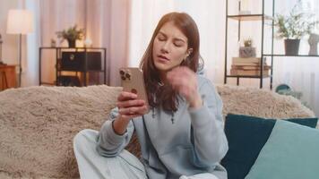 Young woman on sofa using smartphone expressing deep disappointment due to bad news or losing a game video