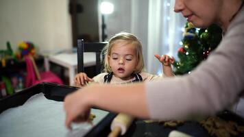 Mother with a little daughter lay out curly gingerbread cookies on a baking sheet on the table video