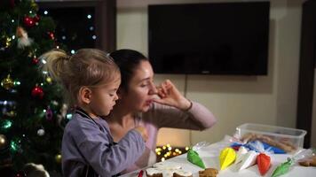 Mom puts icing-covered cookies aside while sitting next to a little girl video