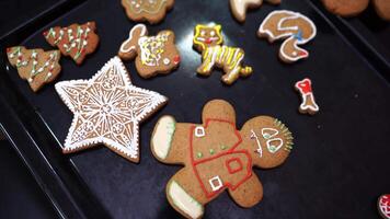 Decorated with colored icing Christmas gingerbread cookies lie on a baking sheet video