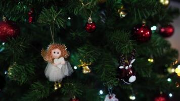 Angel figurine and bells hang on the green branches of a Christmas tree video