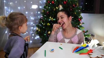 Mom and little girl clink Christmas cookies and eat them at the table video