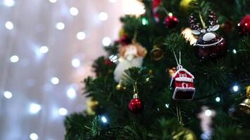 Toy house, a deer and bells hang on the green branches of a spruce video