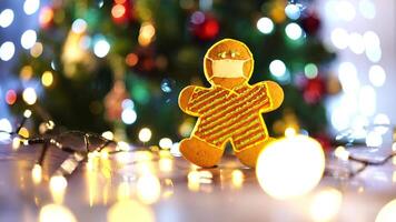 Cookie in the shape of a man in a protective mask stands on a table among luminous garlands video