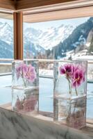 Flowers frozen in ice cubes on a table overlooking snowy mountains in a modern cabin setting photo