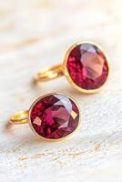 Dark cherry-colored ring and earrings showcase large stones with gold accents against a soft, light setting photo
