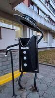 A creatively designed trash can resembling a figure in a tuxedo, showcasing artistic public furniture that encourages waste disposal in a fun way. photo