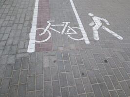 A bicycle lane and pedestrian symbol painted on the pavement, indicating designated paths for cyclists and walkers in an urban setting. photo