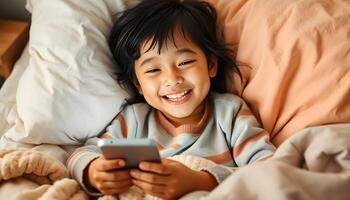 A young boy smiles while laying in bed with a cell phone photo