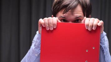 Office worker hiding behind red folder on abstract background video