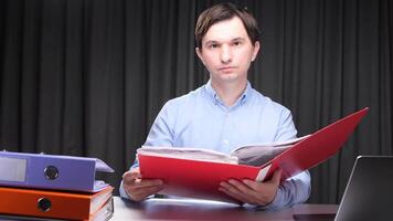 Office worker reading documents in a red folder at night video