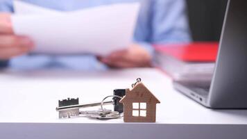 Real estate agent reviewing documents with house keys and small wooden house on desk video