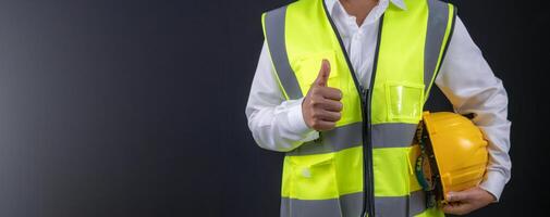 Civil engineer architect standing holding a safety helmet on dark background, Construction site plans to build high-rise buildings, Engineer building concept, Background for with copy space. photo