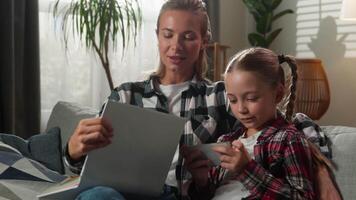Caucasian family at home living room little girl child kid daughter gadget addict dependency addiction mobile phone smartphone game playing ignore mother woman trying reading book offering shrug video