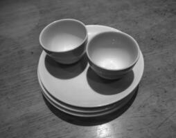 Two cups of tea on stack of small plates in black and white photo style, deep of field selective focus