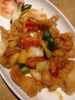 Sweet and sour fried flour fish cooked with vegetables served on a white plate, close up view, deep of field selective focus. Can be used for food menu photos. photo