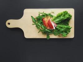 Sliced ham with a green lettuce leaves on a cutting board. photo
