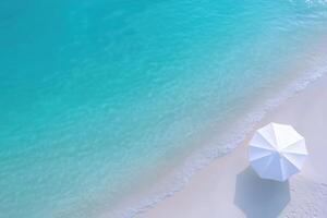 White umbrella on the beach with turquoise water and white sand, top view photo
