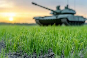 Close-up of a green spring field with a military tank in the background on sunset photo