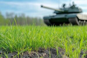 Closeup of spring grass growing in soil with military tank in background photo