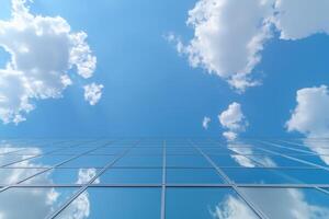 Reflection of blue sky and white clouds in windows of modern office building photo