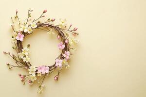 beautiful spring composition elegant floral wreath made of twigs and pastel flowers top view on light yellow background with copy space photo