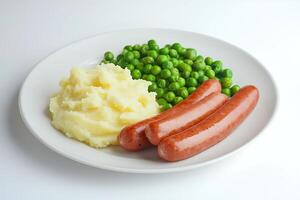 close-up of a white ceramic plate with delicious mashed potatoes with sausages and green peas on a white background photo