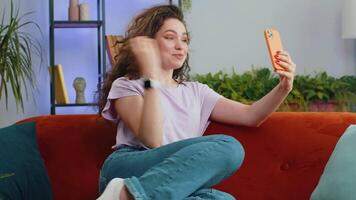 Happy excited young woman making phone call conversation loudspeaker talking with friend at home video