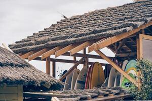 An image of the thatched roof of a wooden hut showing the storage room for a surfboard. With space to copy photo