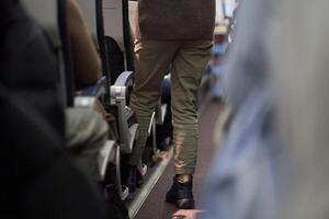The man puts things on the shelf. Passengers sit along the row in the plane in their seats. The concept of travel. photo