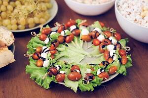 Homemade appetizer of cherry tomatoes and cottage cheese on skewers on a plate . Space for the text. photo