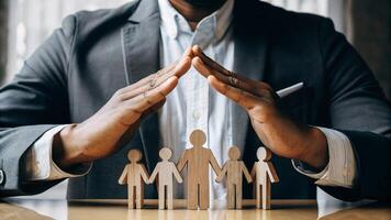 A man in a suit is holding up wooden people with his hands photo