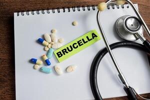 Concept of Brucella write on sticky notes isolated on Wooden Table. photo
