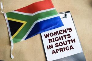 Concept of Women's Rights In South Africa write on paperwork and African flag isolated on Wooden Table. photo