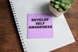 Concept of Develop Self Awareness write on sticky notes isolated on Wooden Table. photo