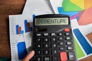 Concept of Debenture write on Calculator isolated on Wooden Table. photo