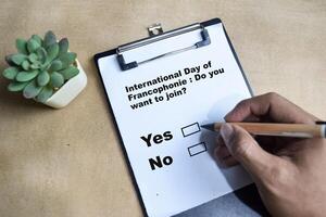 Do you want to Join Yes or No International Day of Francophonie write on paperwork isolated on Wooden Table. photo