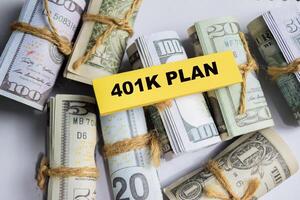 Concept of 401K Plan write on sticky and dollars notes isolated on Wooden Table. photo